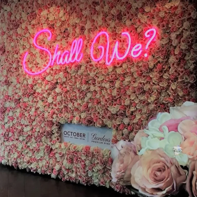 flower wall with pink neon lighting filled with roses